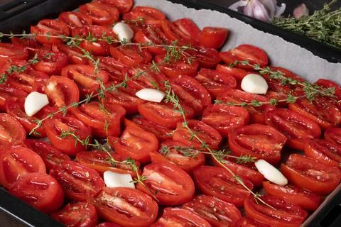 Tomatoes laid out on a baking sheet for cooking in the oven. Stock Photos