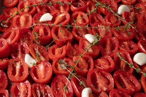 Tomatoes laid out on a baking sheet for cooking in the oven. Stock Photos