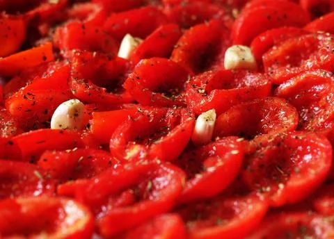 Tomatoes lie on a baking sheet, ready to bake. Sun-dried tomatoes with garlic. Stock Photos