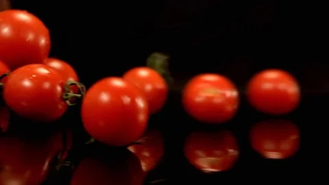 Tomatoes roll on the black surface Stock Footage 76471468