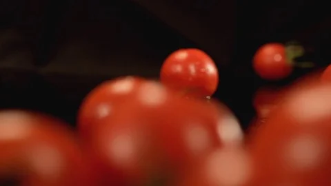Tomatoes roll on the black surface Stock Footage 76471627