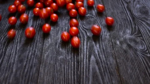 Tomatoes roll over the screen in slow motion on wooden background Stock Footage 74075392
