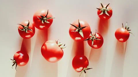 Tomatoes scattered on beige kitchen table, light and shadows, food background Stock-Fotos