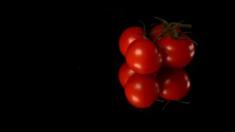Tomatos lay on black surface cinematic image. Water falls on it Stock Footage 113005259
