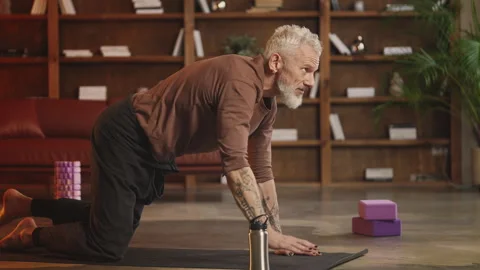 Toned man in his 50s practices bird dog pose on yoga mat, active lifestyle Stock Footage 343507248
