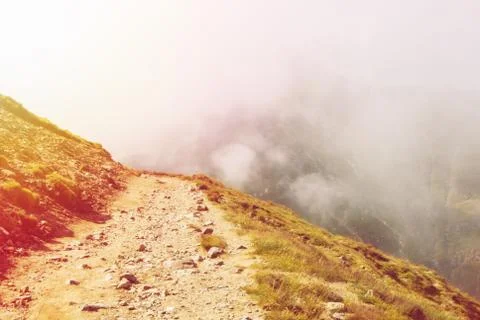 Toned serpentine path going down in the Carpatian mountains and a big fog clo Stock Photos