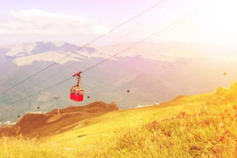 A toned view to bright red cableway cabin moving to the top of the mountain o Stock Photos