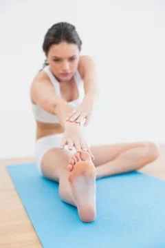 Toned woman doing the hamstring stretch on exercise mat in fitness studio Stock Photos