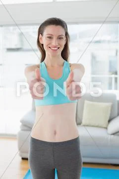 Toned woman gesturing thumbs up in fitness studio Stock Photos