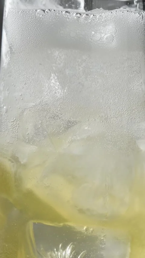 Tonic water foams over ice and apple cider in glass as sparkling drink fills in Stock Footage 345487232