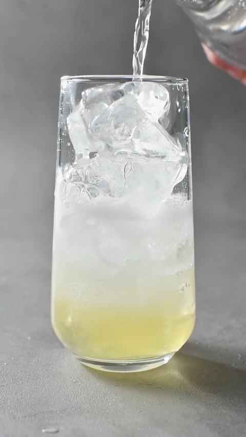 Tonic water pours over apple cider and ice, creating foam and bubbles in Stock Footage 345487130