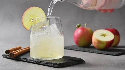Tonic water pours over iced apple cider during preparation of apple cider cold Stock Footage 345556852