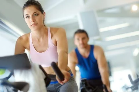 Toning those legs. A man and woman exercising in spinning class at the gym. Stock Photos