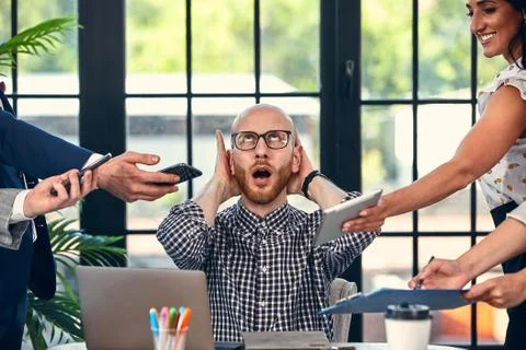 Too many work. Selective focus of young business man surrounded by colleagues Stock Photos