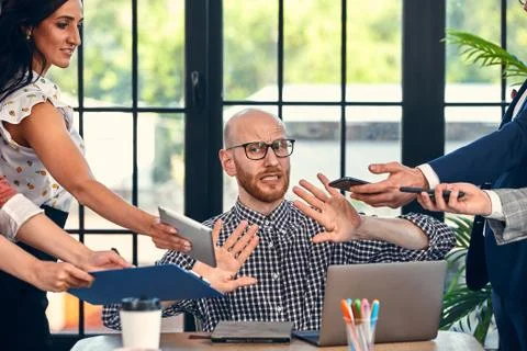 Too many work. Selective focus of young business man surrounded by colleagues Stock Photos