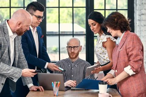 Too many work. Selective focus of young business man surrounded by colleagues Stock Photos