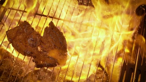 Too well done beef steak on the grill in flames. Slow motion. Stock Footage 135607868