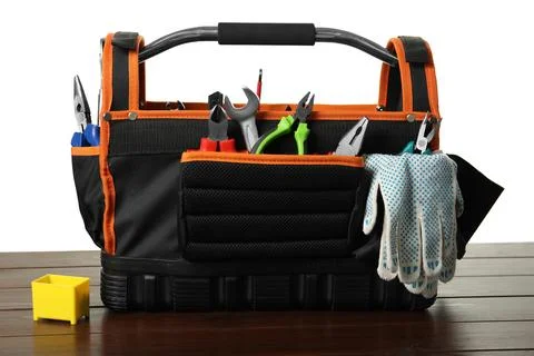 Tool bag with different pliers, work gloves and wrench on wooden table agai.. 库存照片