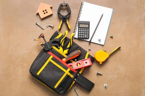 Tool bag with set of construction tools and notebook on beige grunge backgrou Stock Photos