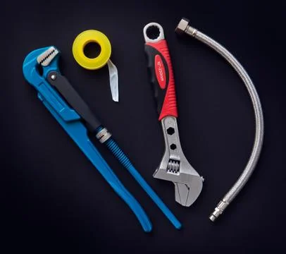 Tools, adjustable wrenches, flexible hose and  thread seal tape on dark backg Stock Photos