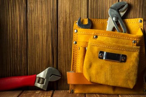 Tools and instruments in leather bag on wooden background. Stock Photos