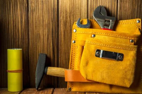 Tools and instruments in leather bag on wooden background. Stock Photos