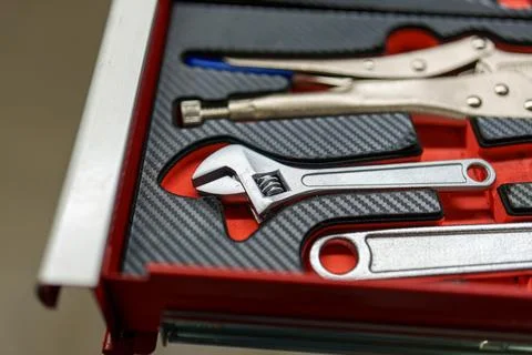 Tools are organized in a red toolbox with a focus on a wrench and pliers on.. Foto stock