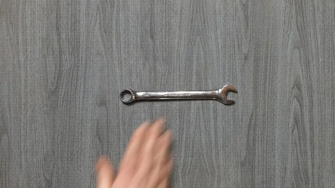 Tools being placed in frame by hand with grey wood texture backdrop Stock Footage 121004565