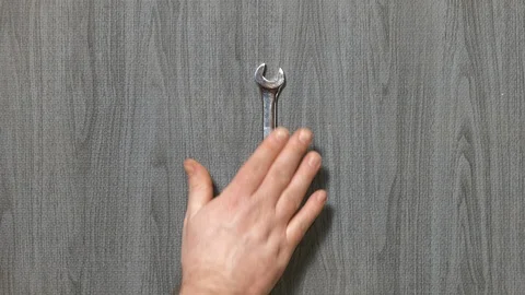 Tools being placed in frame by hand with grey wood texture backdrop Stock Footage 121004571