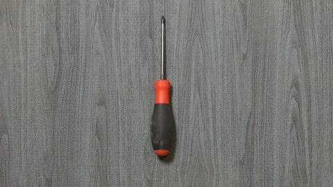 Tools being placed in frame by hand with grey wood texture backdrop Stock Footage 121007577