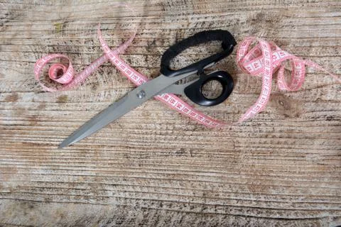 Tools for cutting clothes. Scissors and centimeter on the wooden table. Stock Photos