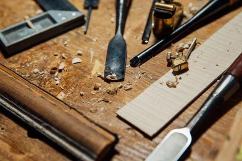 Tools on the desktop in the workshop. Making a violin. Wood shavings and dust Stock Photos