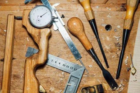 Tools on the desktop in the workshop. Making a violin. Wood shavings and dust Stock Photos