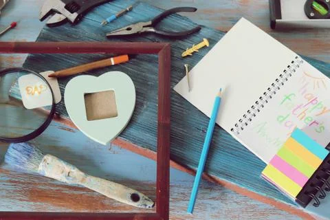 Tools, frame, notebook, congratulation on a wooden table, top view, father's day Stock Photos