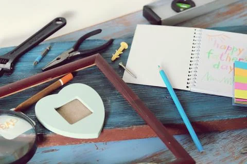 Tools, frame, notebook, congratulation on a wooden table, top view, father's day Stock Photos