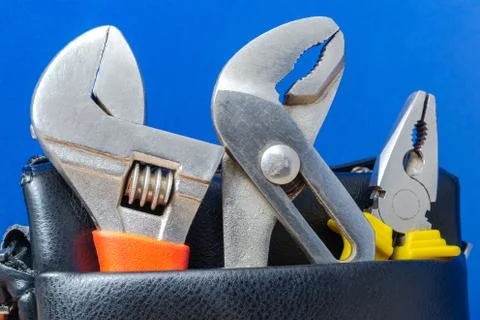 Tools in a leather bag on a blue background - wrenches and pliers. Stock Photos