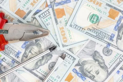 Tools lying over 100 dollars banknotes background. Pliers and screwdriver aga 写真素材