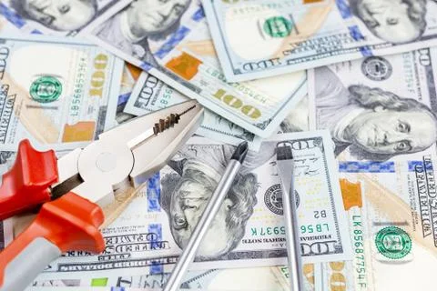 Tools lying over 100 dollars banknotes background. Pliers and screwdriver aga 스톡 사진