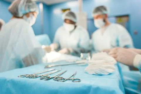 Tools for the operation in the foreground and a team of surgeons in the Stock Photos