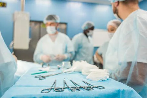 Tools for the operation in the foreground and a team of surgeons in the Stock Photos