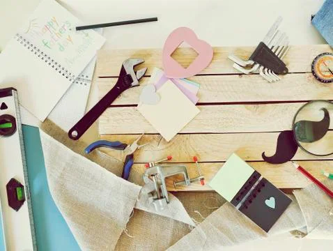 Tools, paper mustache, notepad, congratulation on a wooden table, top view Stock Photos
