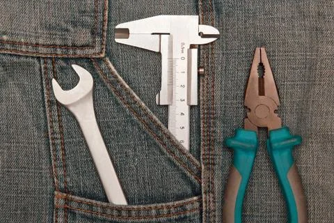 Tools pliers, spanner and micrometer in jeans pocket Stock Photos