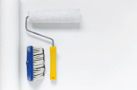 Tools for wallpapering, paint roller and a brush on white wallpaper roll with Stock Photos