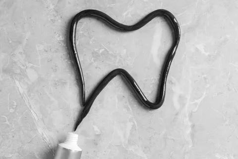 Tooth drawn with charcoal toothpaste on light grey table, flat lay 스톡 사진