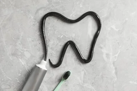 Tooth drawn with charcoal toothpaste on light grey table, flat lay 스톡 사진