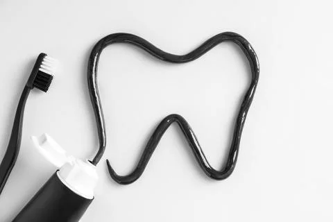 Tooth drawn with charcoal toothpaste on white background, top view 스톡 사진