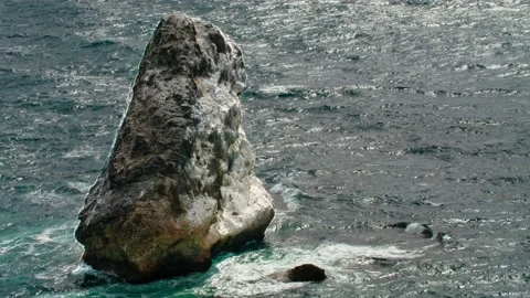 A tooth-shaped sea cliff surrounded by water. Long shot taken with a tripod Stock Footage 217731231