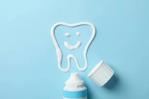 Tooth with smile drawn in toothpaste on blue background Foto stock