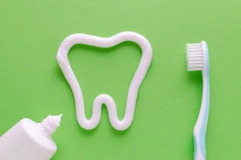 A tooth from toothpaste, teeth care concept, toothbrush on green background Stock Photos
