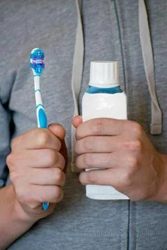 Toothbrush and toothpaste in the hands of a young man. Stock Photos